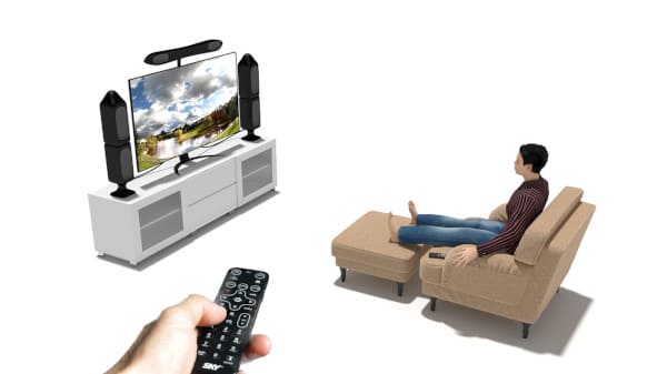 La dissociation pour gérer les émotions : un homme est assis sur son canapé regardant le film d'une émotion négative. Au premier plan, on voit une main qui tient une télécommande en direction de la scène.